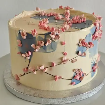 Buttercream cake with pink blossoms and soft blue painted details
