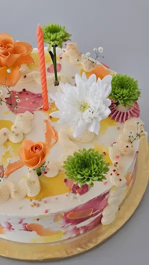 Floral cake with orange candle and fresh flowers