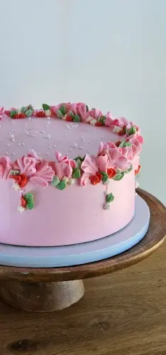 Pink buttercream cake with piped flower border and pearl details