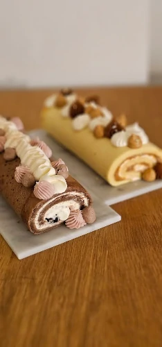 Two decorated roll cakes on serving boards