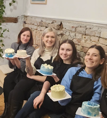 Cake workshop participants sitting together and holding their decorated cakes