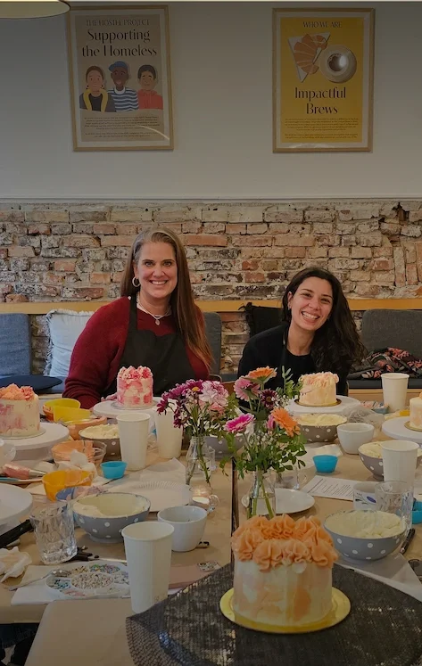 Cake decorating workshop table with participants and finished buttercream cakes